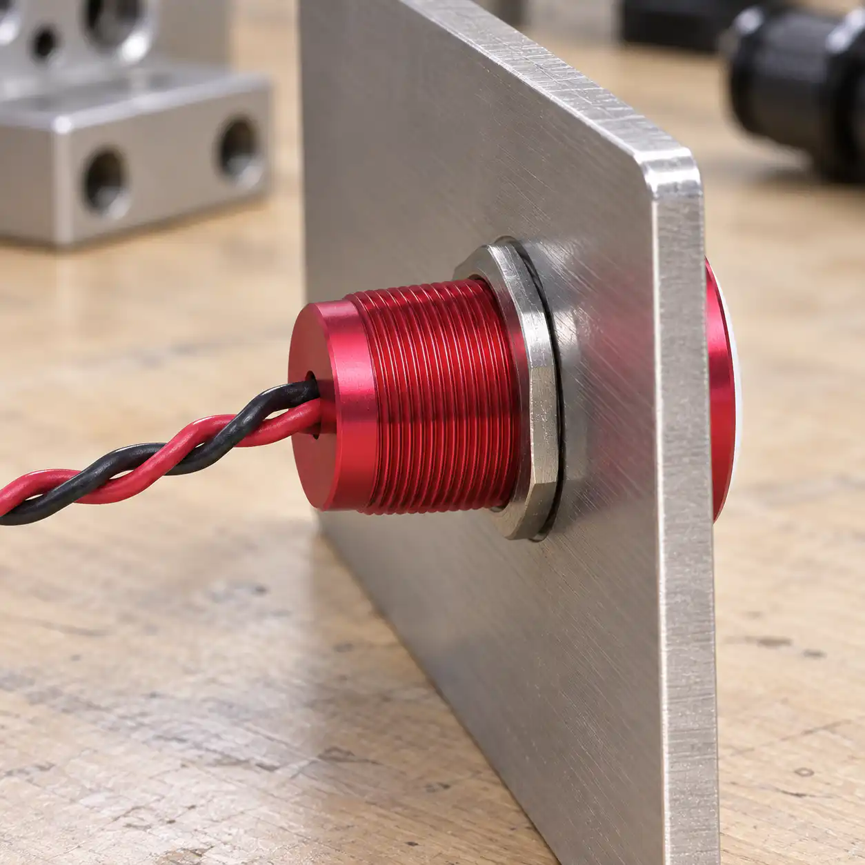 Rear clearance for a panel-mounted piezo switch Rear side of a red piezo switch showing its red and black leads through a dry panel coupon