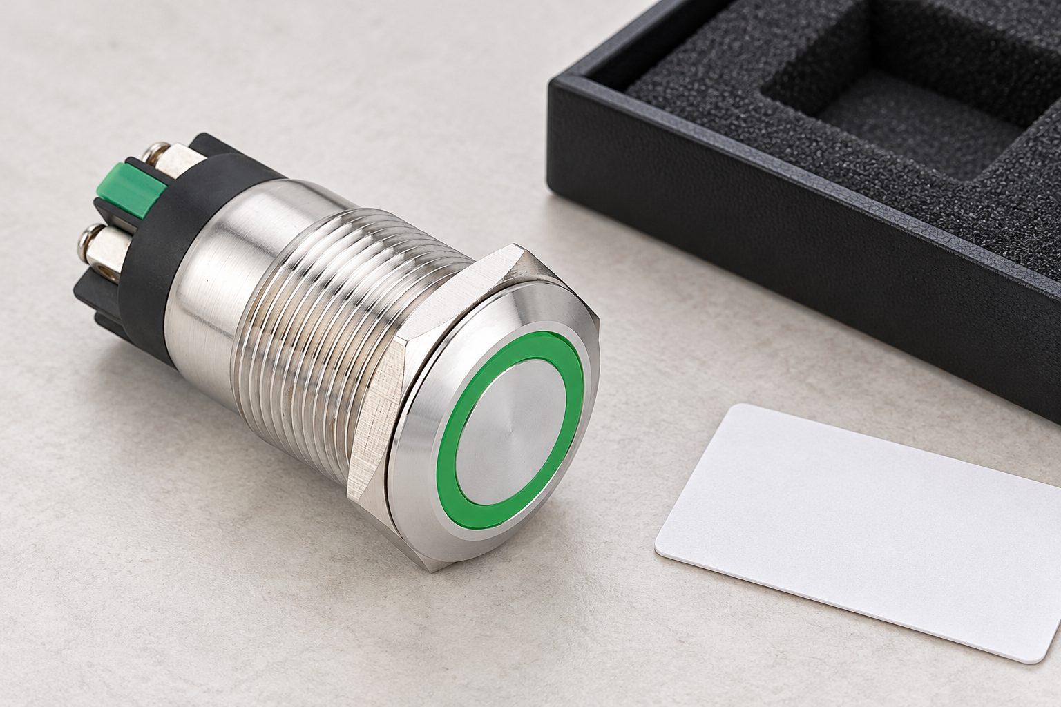 Reference-based illustration of a green-ring stainless push button beside a separate padded tray and sample card